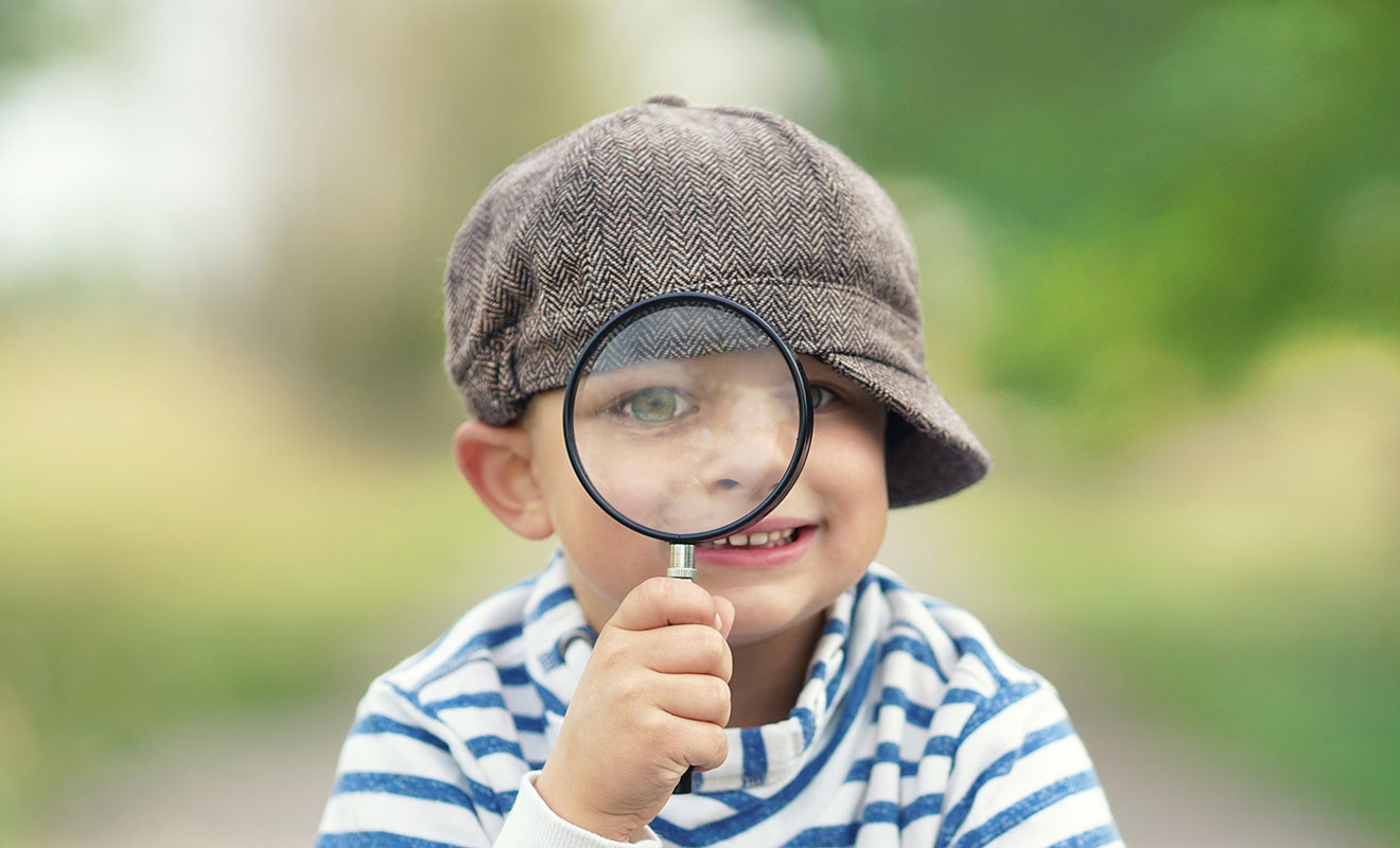 bambino che guarda attraverso una lente di ingrandimento